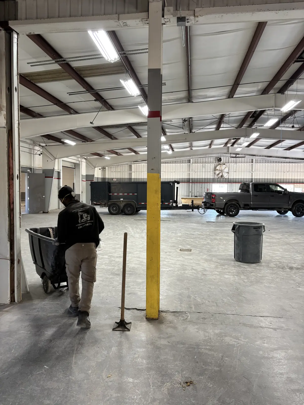 Crew clearing debris to bins during a strip out inside an existing warehouse shell